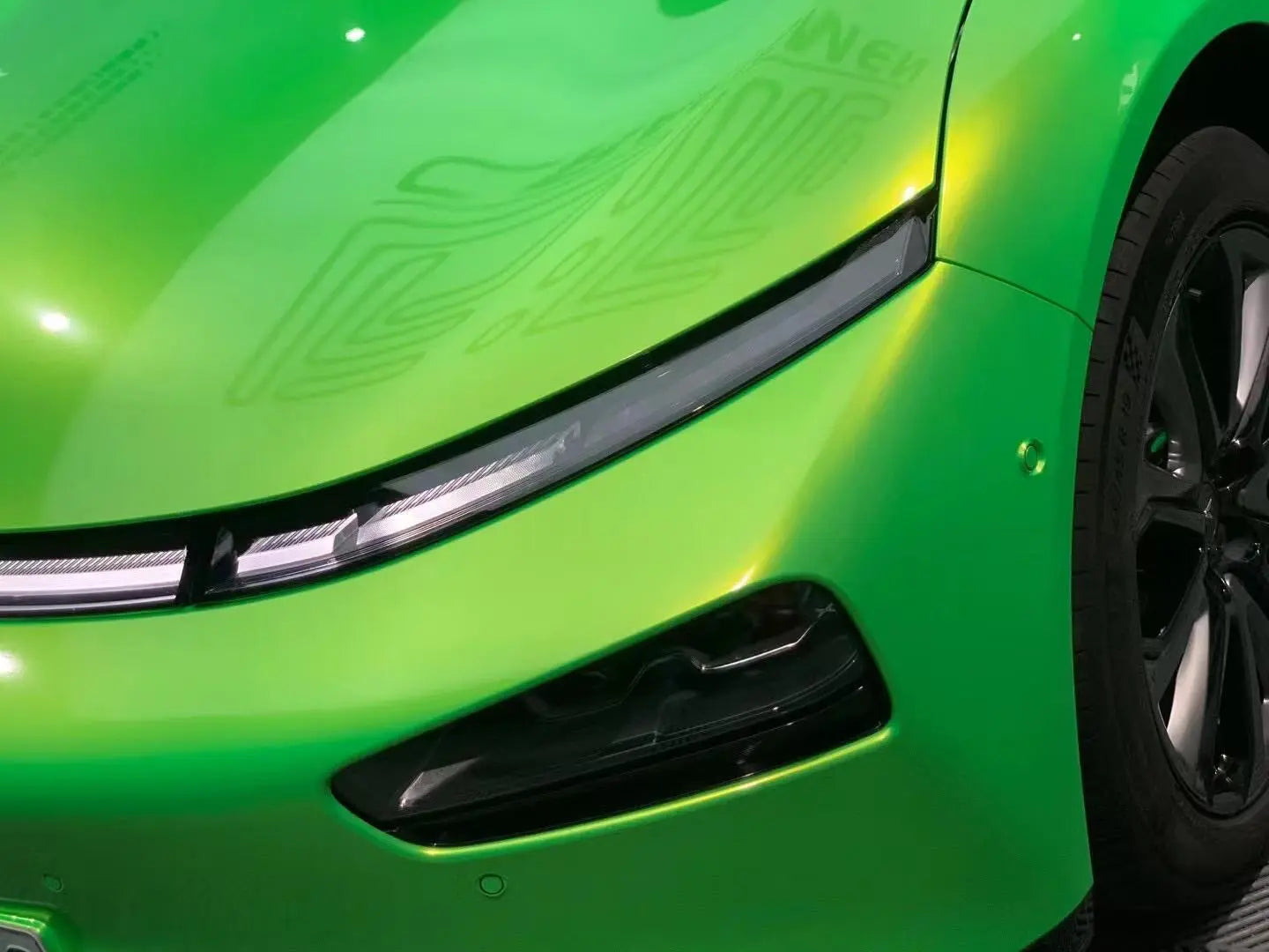 Close-up of Neon Gold Green film on Xpeng P7 front bumper - precise cutting on complex curves - Kaleido