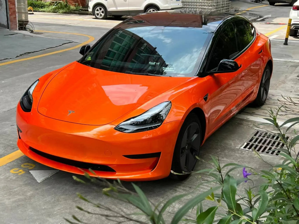 Close front-left view of Neon Gold Orange wrapped Tesla Model 3 - vibrant color display - Kaleido