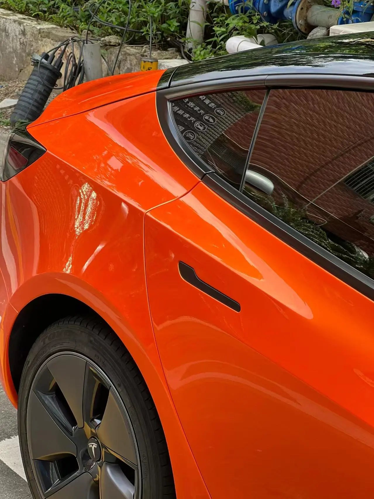 Close-up of Neon Gold Orange film on Tesla Model 3 rear door - precise edge work - Kaleido