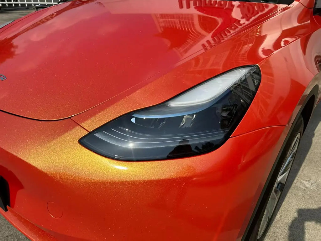 Close-up of Neon Gold Orange film on Tesla Model Y front-left - bumper and headlight details - Kaleido