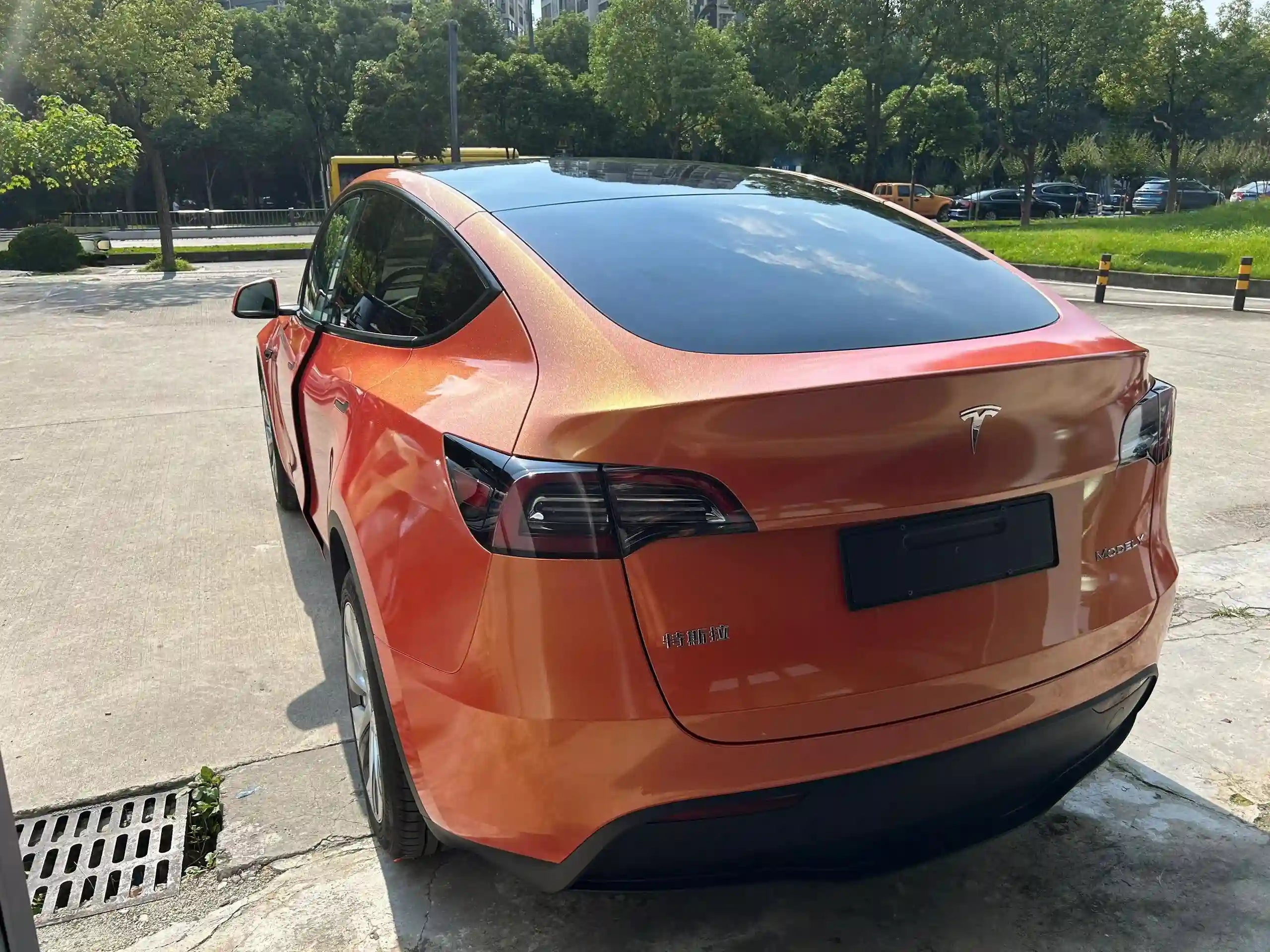 Tesla Model Y in Neon Gold Orange color shift wrap - rear-left view showcasing SUV profile - Kaleido