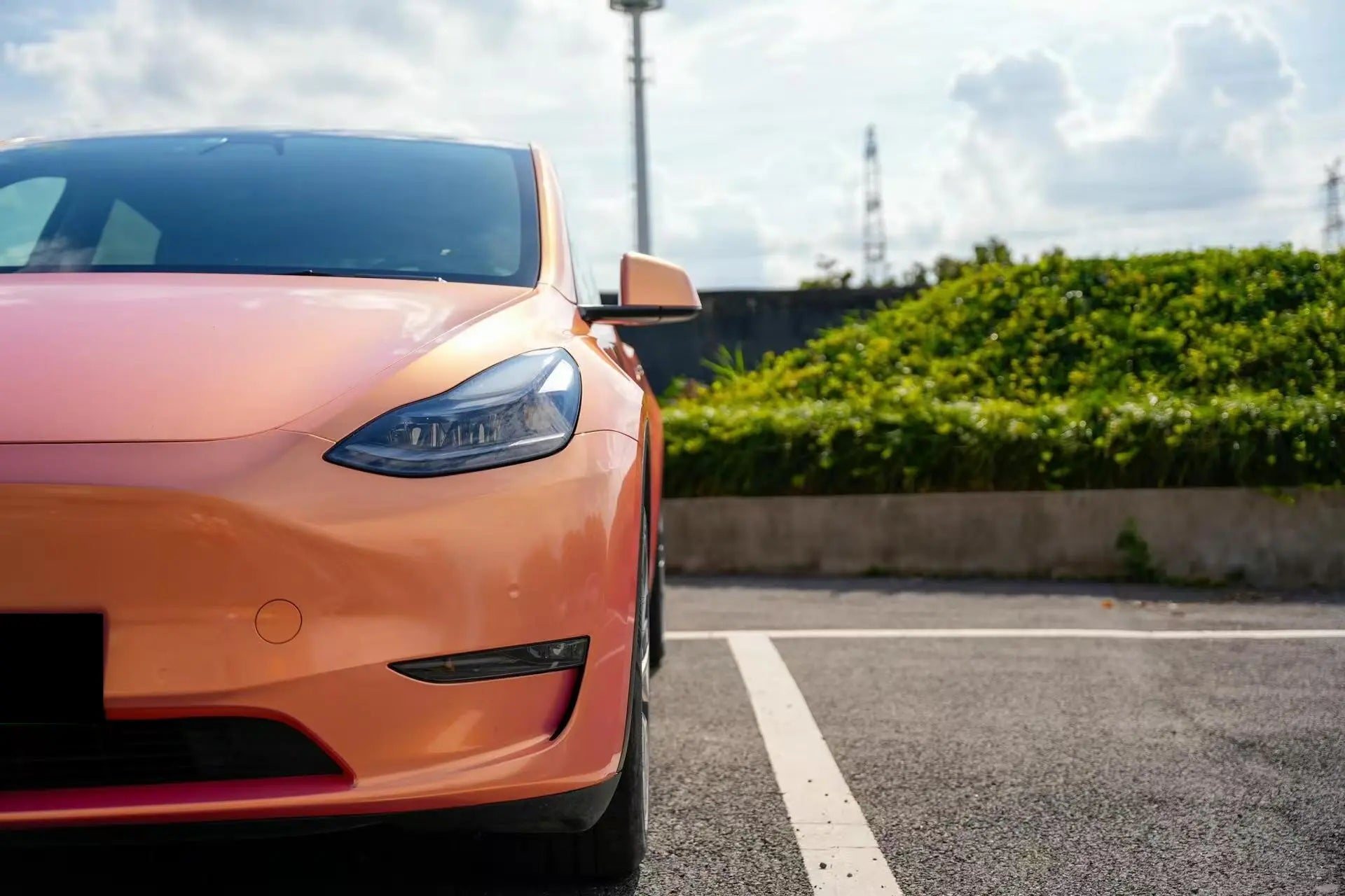 Front-left corner detail of Tesla Model Y in Neon Gold Pink color shift - Kaleido