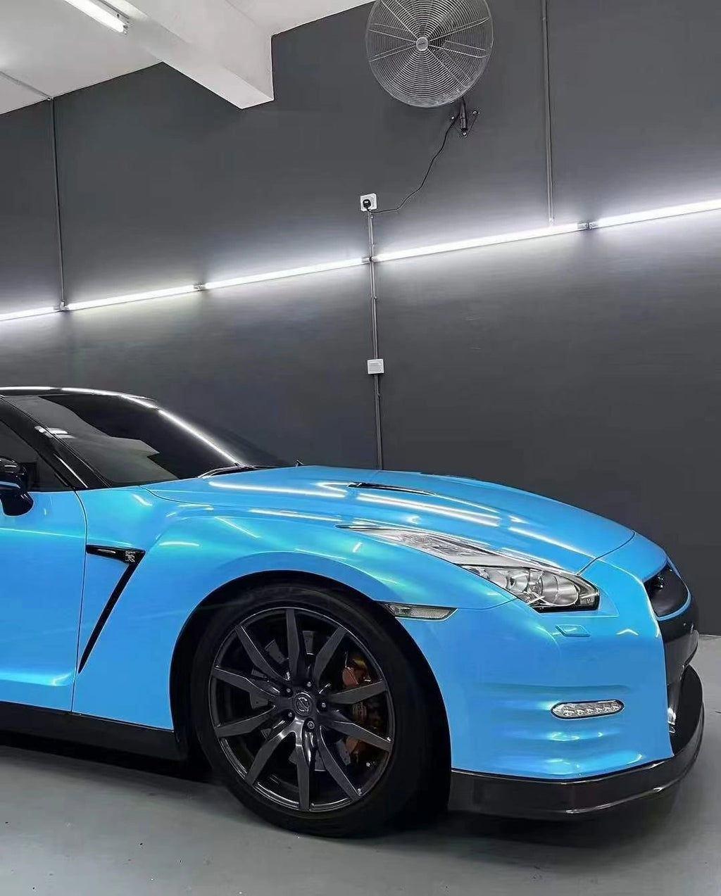 Close-up of Neon Sky Blue film on Nissan GT-R front bumper - precise installation on aggressive styling - Kaleido