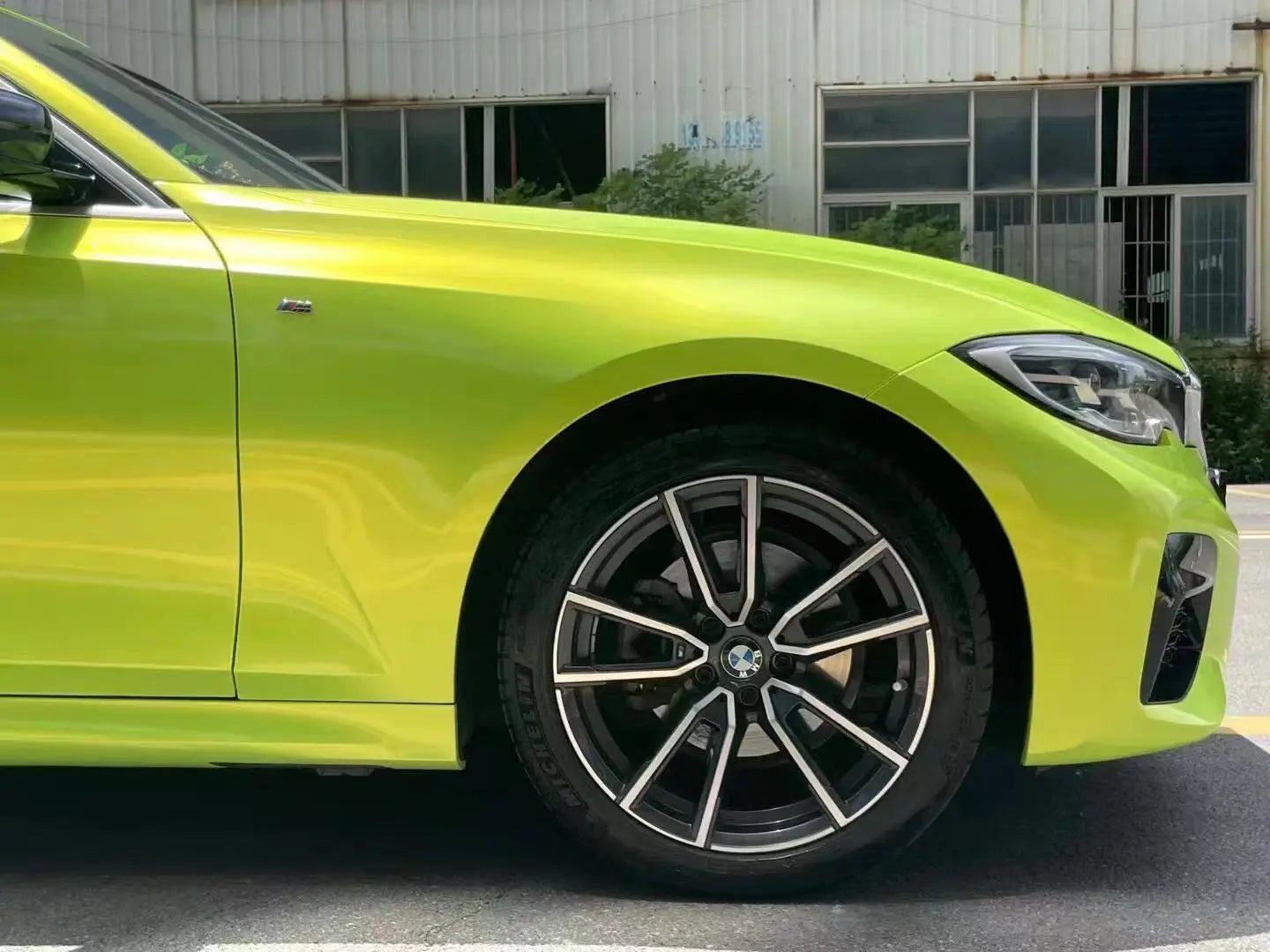 Neon Yellow color shift wrap on BMW 5 Series front-right corner - close-up on headlight and bumper - Kaleido