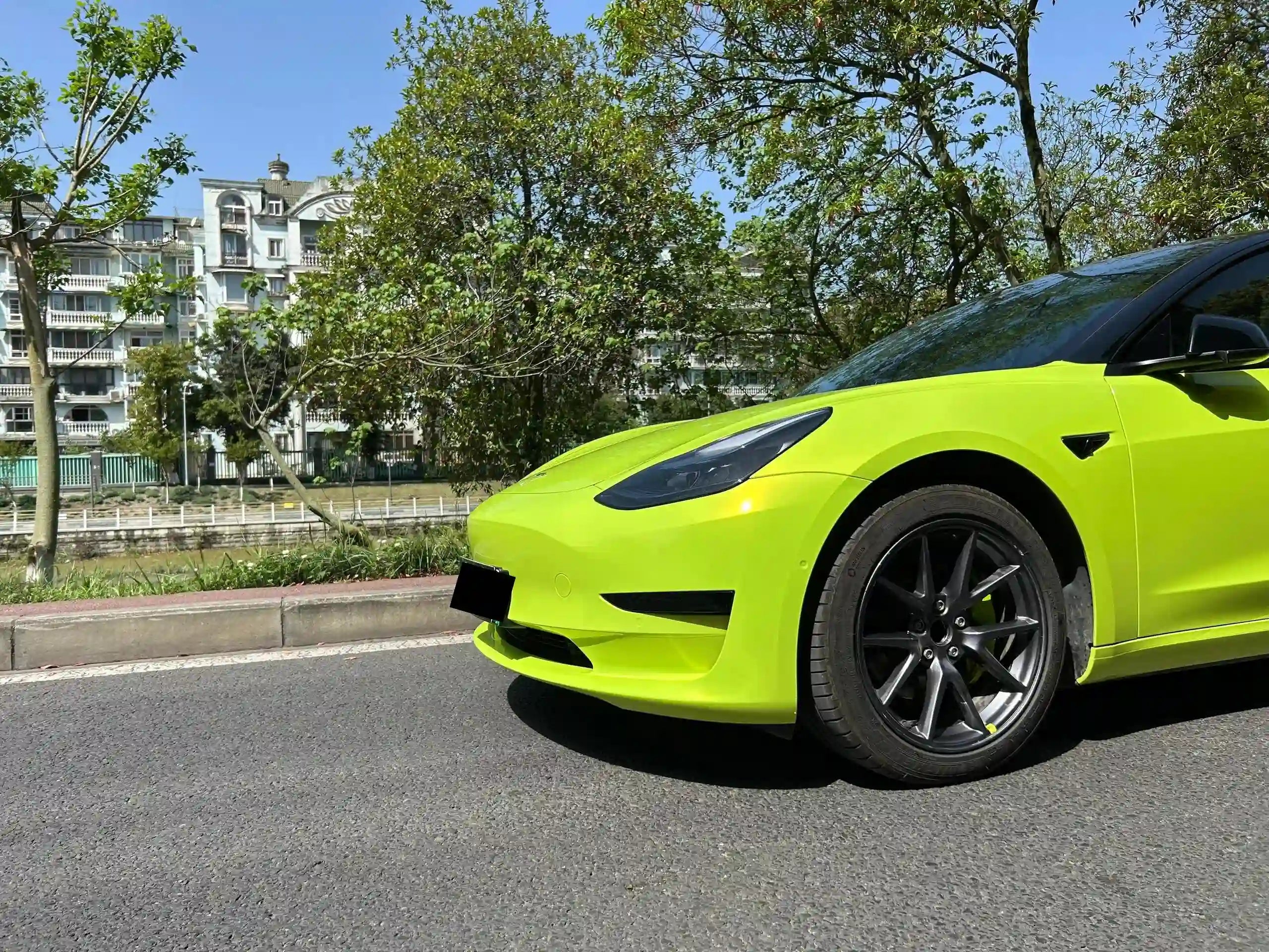 Close-up of Neon Yellow wrap on Tesla Model 3 front-left bumper - Kaleido