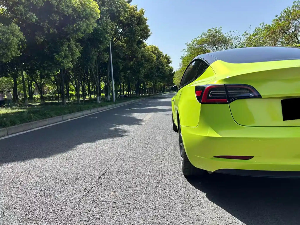 Rear-left corner detail of Tesla Model 3 in Neon Yellow color shift - Kaleido