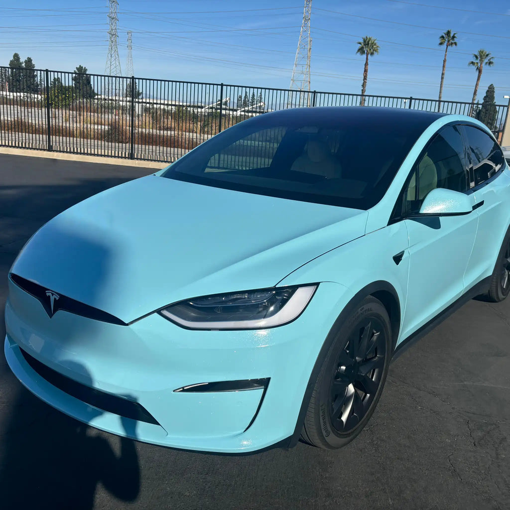 Tesla Model X in Diamond Iridescent Sea Mist Blue vinyl wrap - front-left angle showcasing SUV silhouette - Kaleido