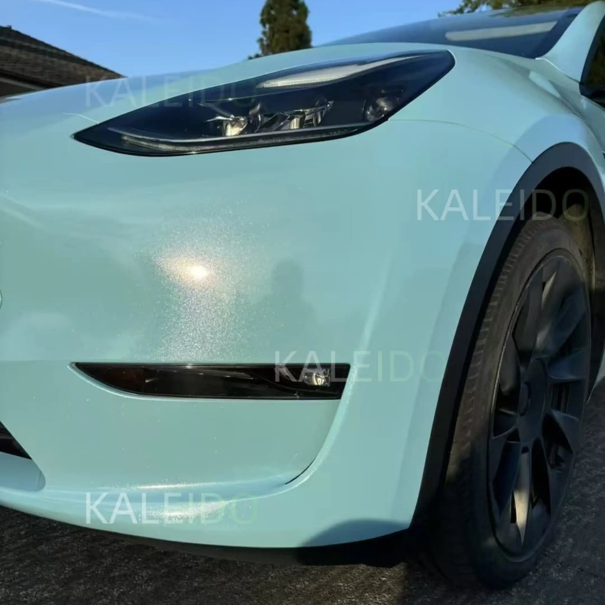 Close-up of Diamond Iridescent Sea Mist Blue film on Tesla Model Y front-left corner - multi-colored pearl detail - Kaleido