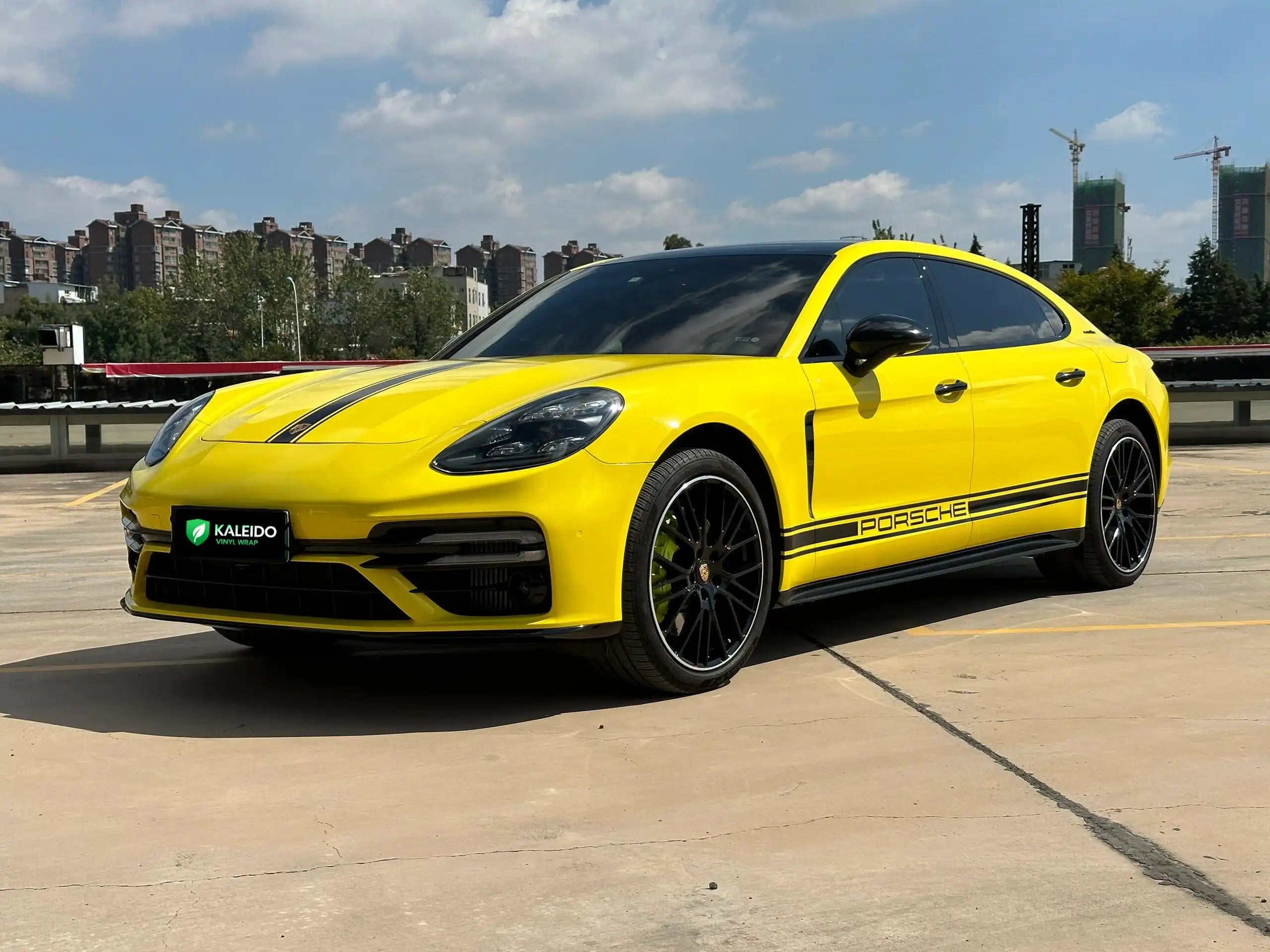 Wide front-left view of a modified Porsche Panamera in bright Gloss Corn Yellow vinyl wrap - Kaleido