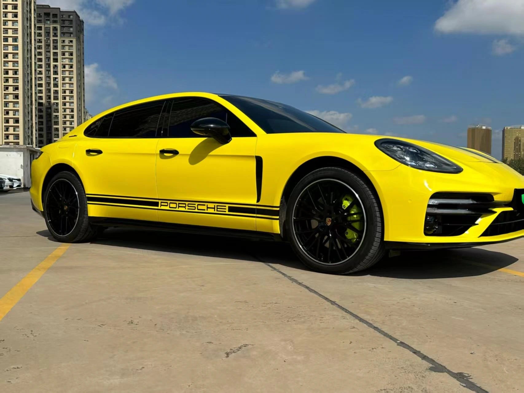 Low-angle front-right shot of a modified Porsche Panamera in Gloss Corn Yellow, emphasizing aggressive stance - Kaleido