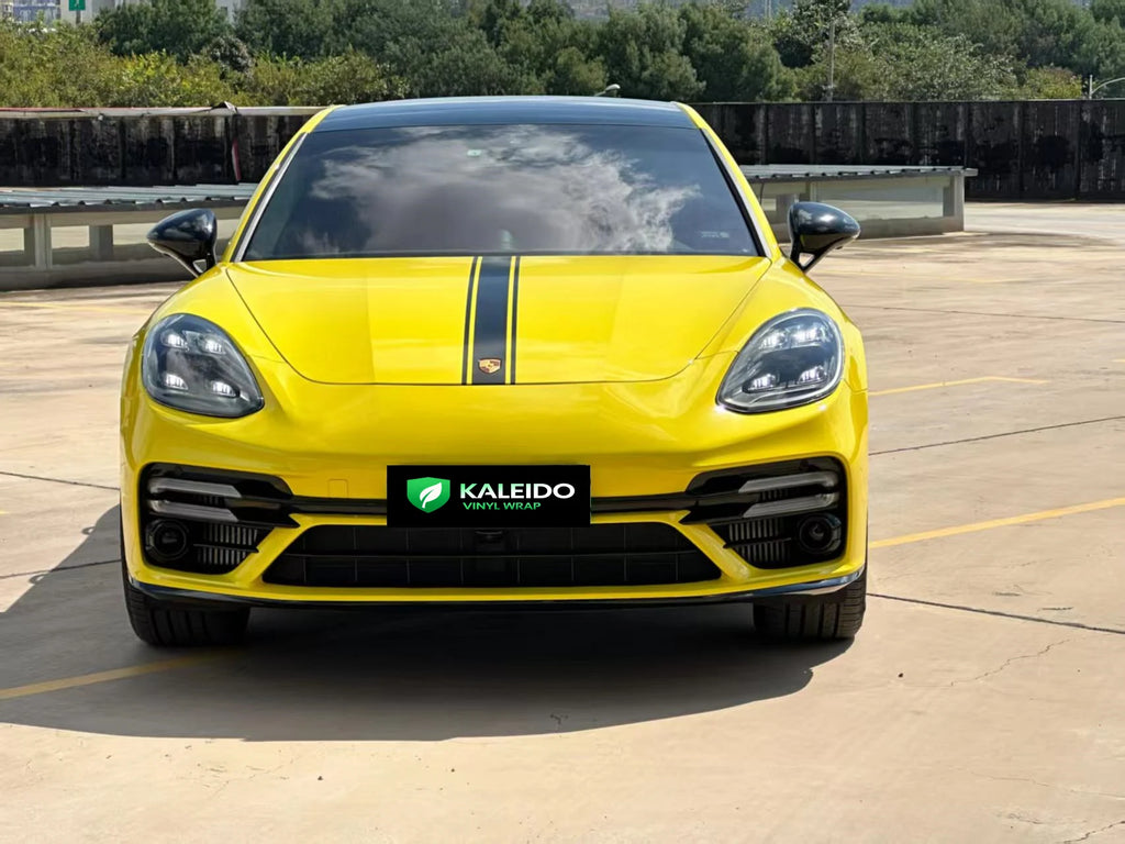 Front view of a modified Porsche Panamera sports sedan wrapped in bright Gloss Corn Yellow - Kaleido