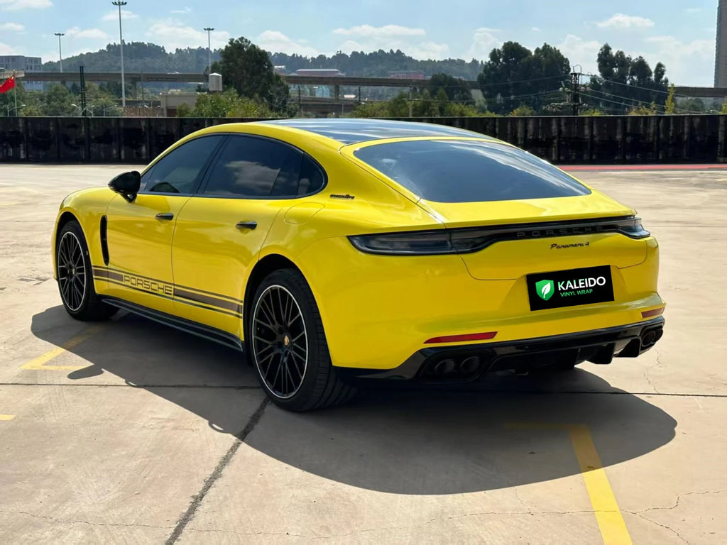 Wide rear-left panoramic view of a Gloss Corn Yellow wrapped Porsche Panamera - Kaleido
