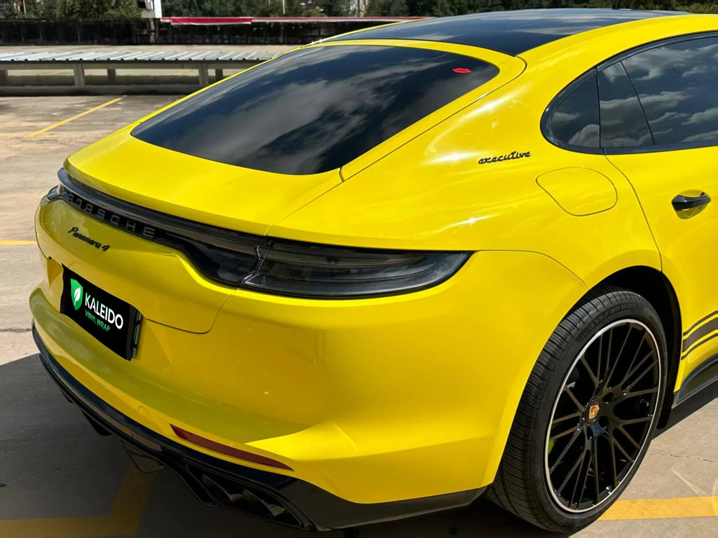 Close-up rear-right detail of a modified Porsche Panamera in Gloss Corn Yellow vinyl - Kaleido