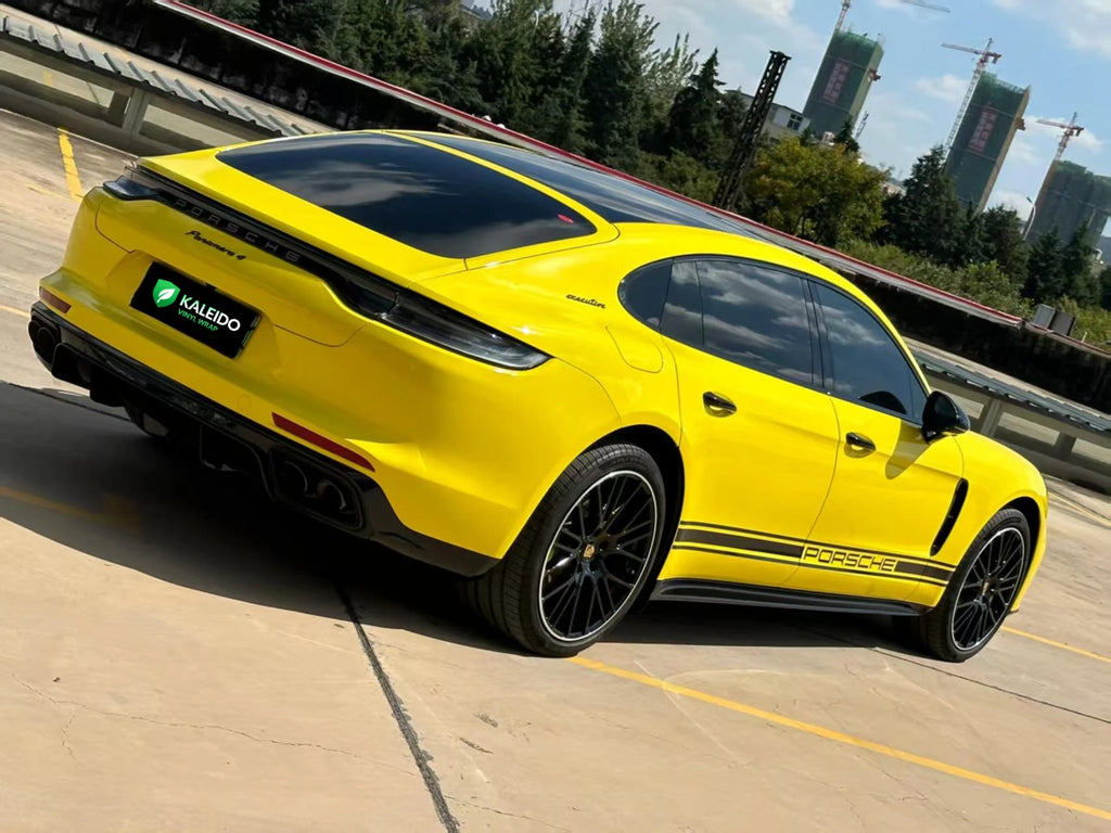 Wide rear-right view of a modified Porsche Panamera with Gloss Corn Yellow vinyl wrap - Kaleido