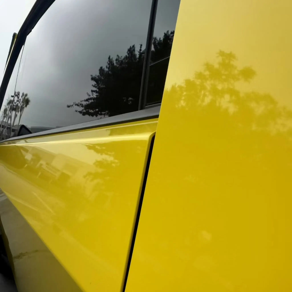Detailed close-up of the Gloss Corn Yellow finish on the Tesla Cybertruck's stainless steel door panel - Kaleido