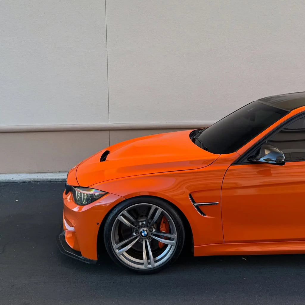 Gloss Hermès Orange film on the front-left corner of a modified BMW M4 (F82) - Kaleido