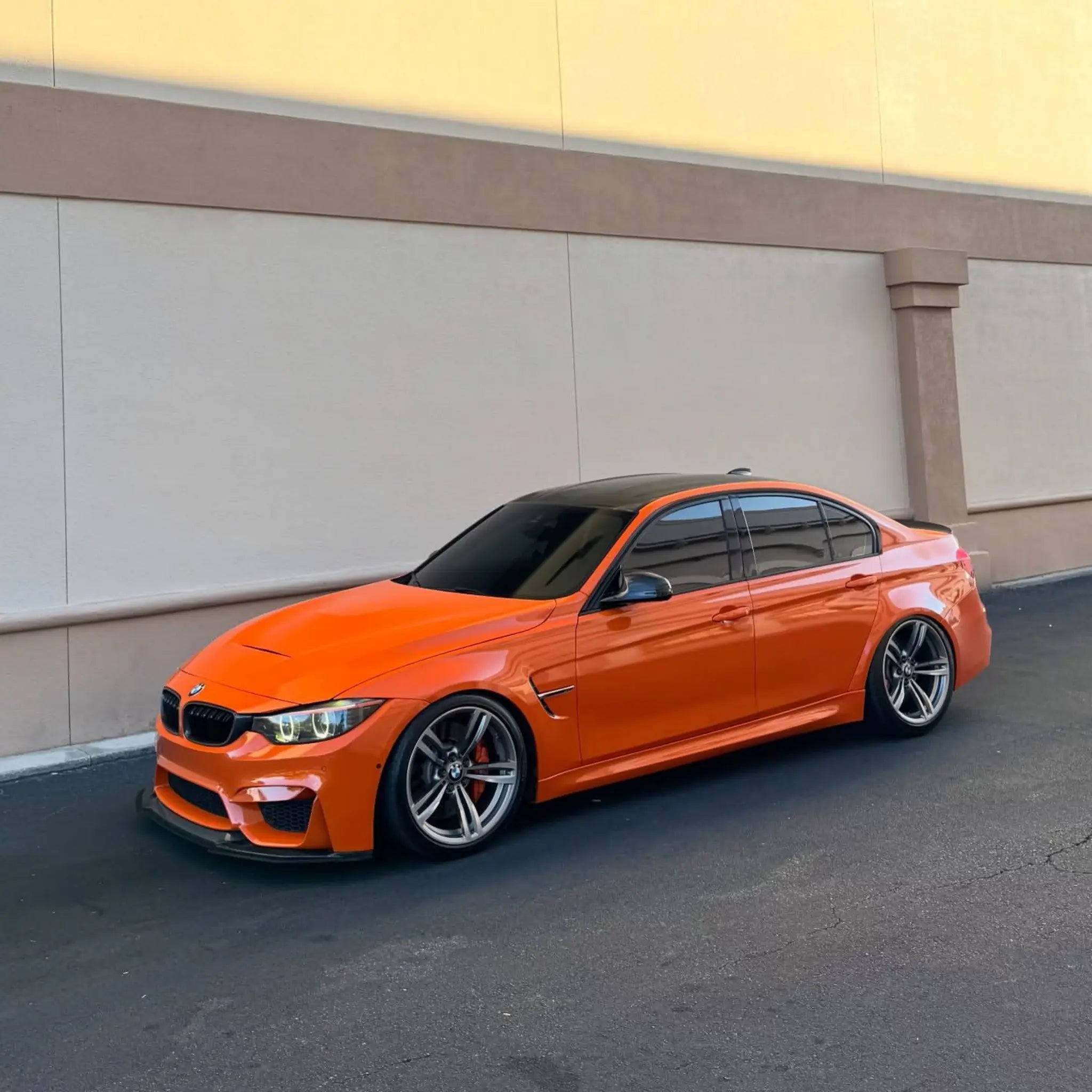 Wide front-left view of a modified BMW M4 (F82) with Gloss Hermès Orange vinyl - Kaleido