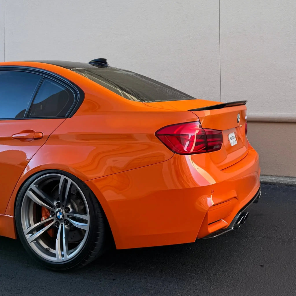 Rear-left corner of a modified BMW M4 (F82) wrapped in Gloss Hermès Orange - Kaleido