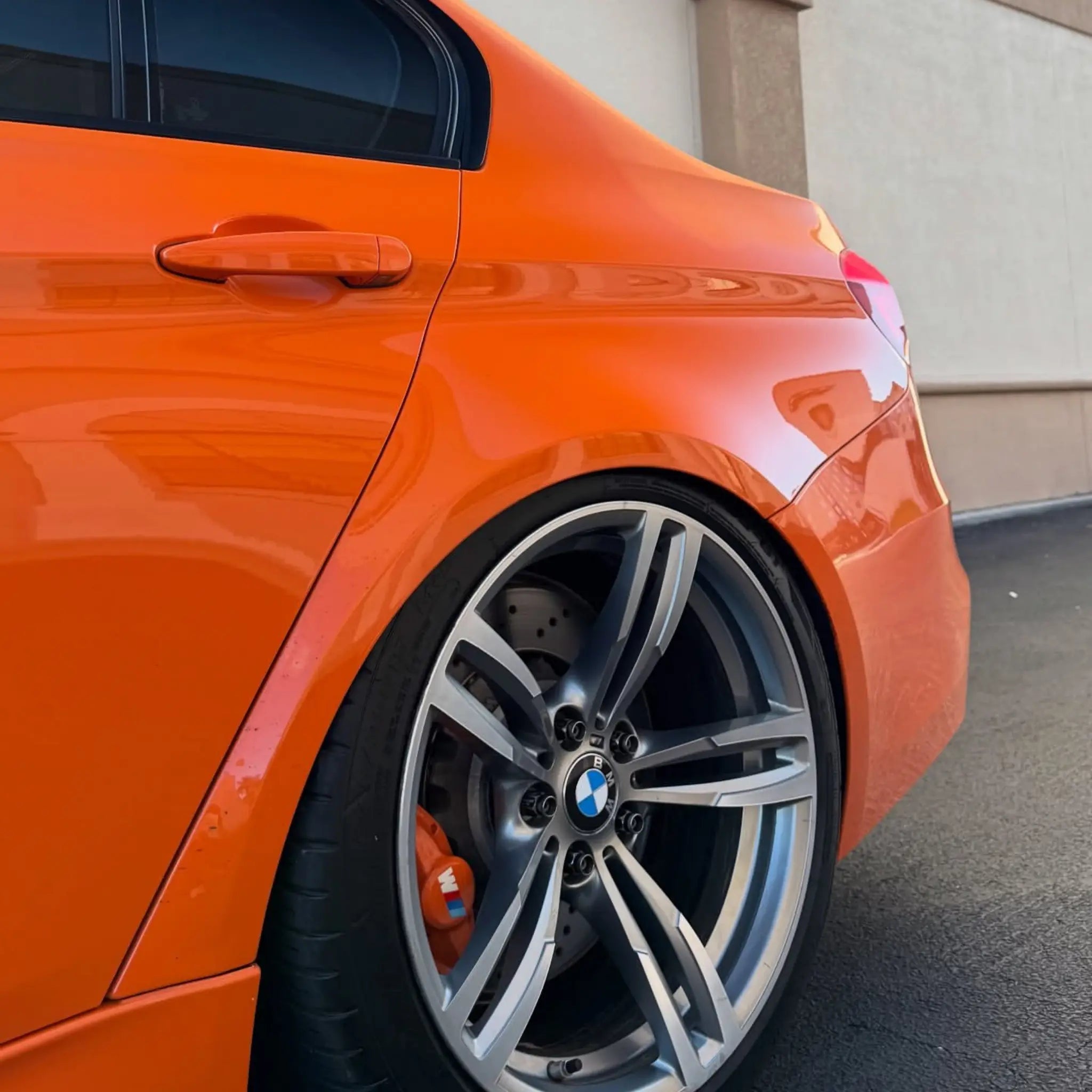 Close-up detail of Gloss Hermès Orange wrap on the modified BMW M4 (F82) left rear - Kaleido