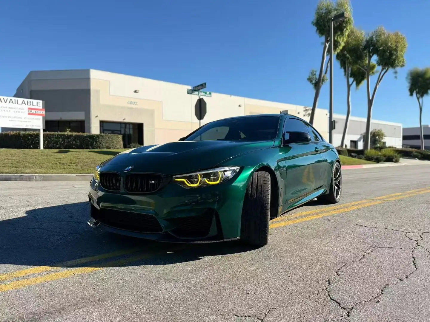 BMW M4 in Gloss Metallic Agate Green vinyl wrap - front-left angle showing aggressive stance - Kaleido