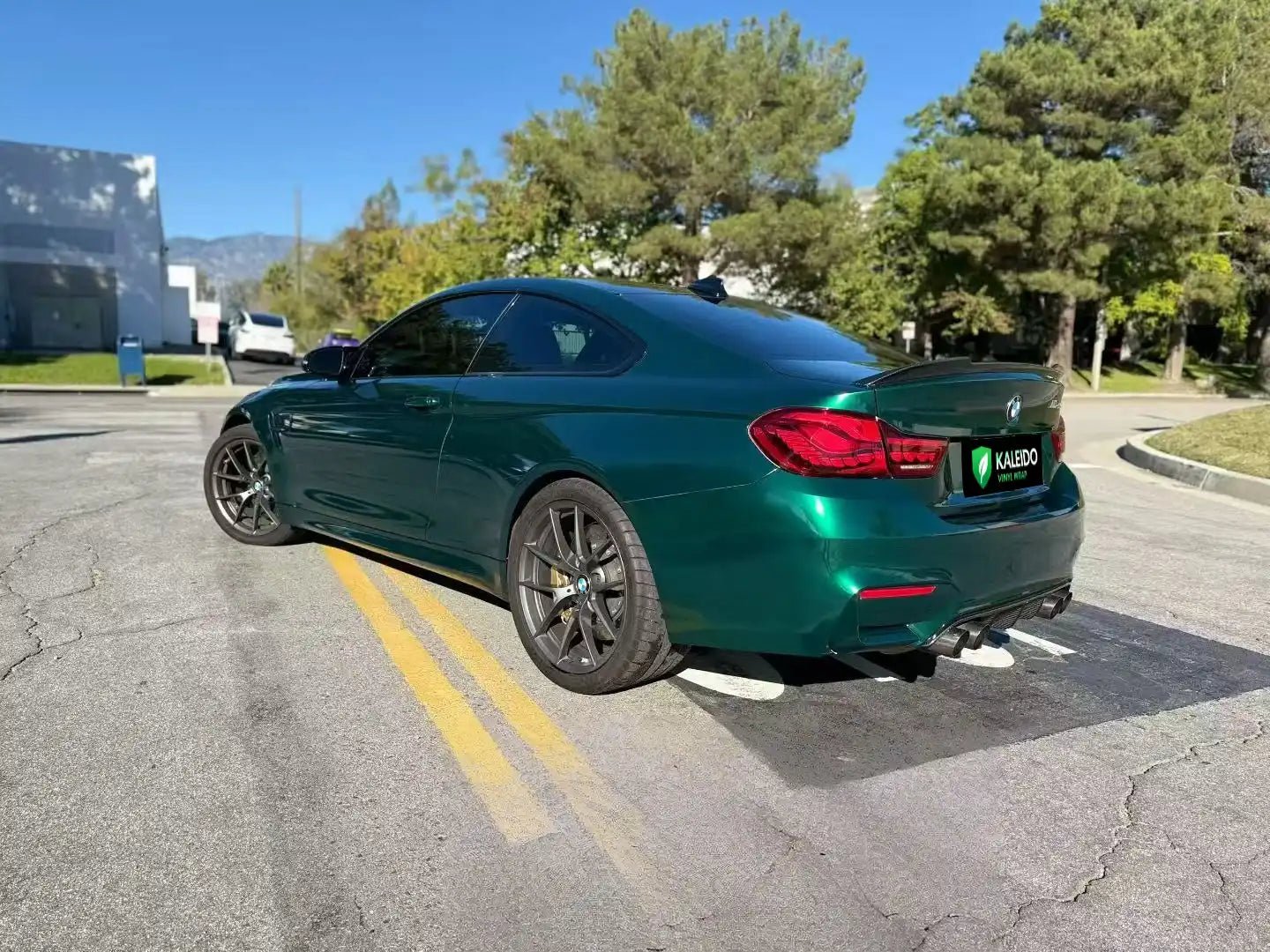 Rear-left view of BMW M4 in Gloss Metallic Agate Green vinyl wrap - Kaleido