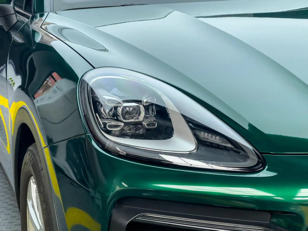 Close-up of Gloss Metallic Agate Green wrap on Porsche Cayenne front-right bumper - Kaleido