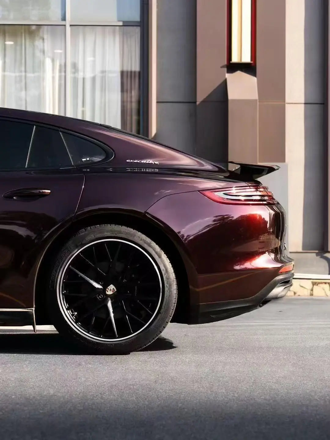 Gloss Metallic Black Rose vinyl on Porsche Panamera left rear corner - Kaleido