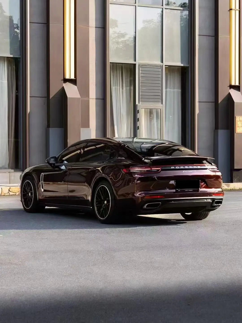 Wide rear-left view of Gloss Metallic Black Rose wrapped Porsche Panamera - Kaleido