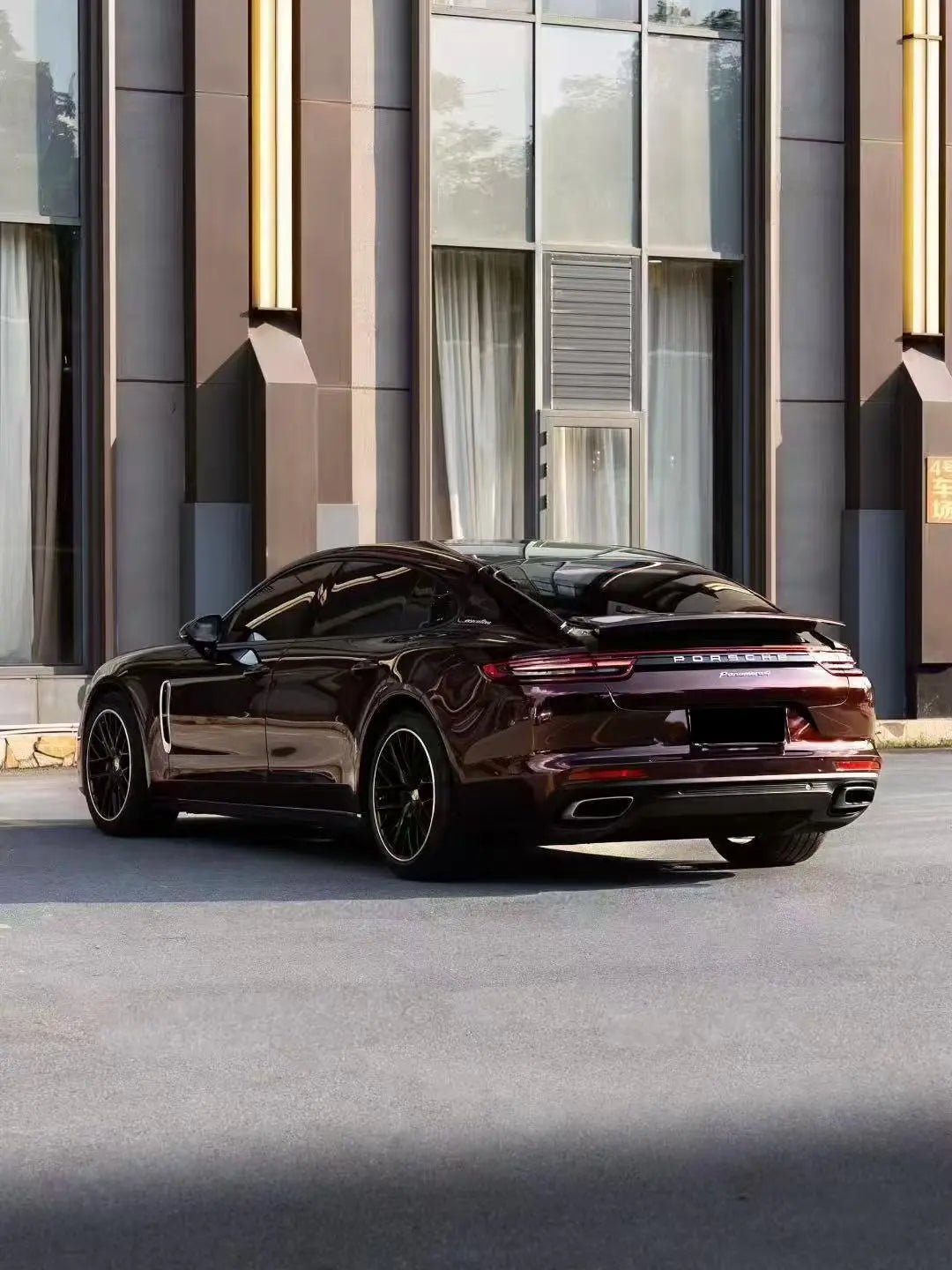 Wide rear-left view of Gloss Metallic Black Rose wrapped Porsche Panamera - Kaleido