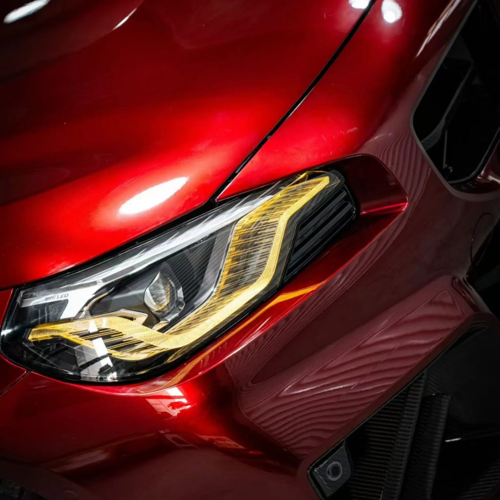 Close-up detail of Gloss Metallic Dragon Blood wrap around BMW M2 left headlight - Kaleido