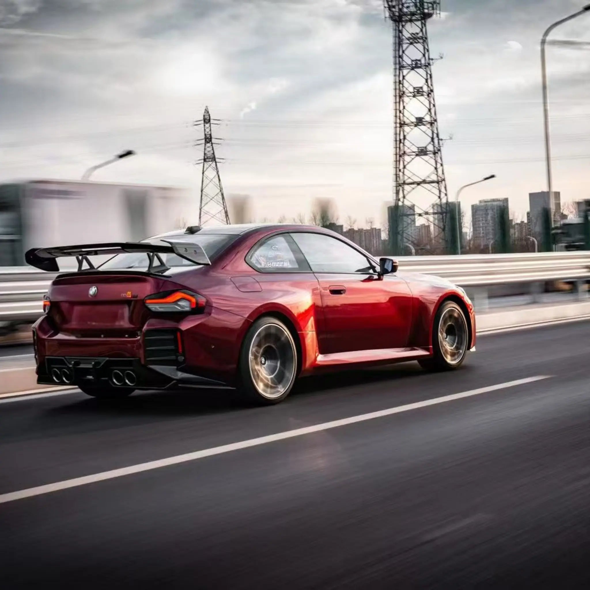 Wide outdoor rear-right view of BMW M2 in Gloss Metallic Dragon Blood wrap - Kaleido