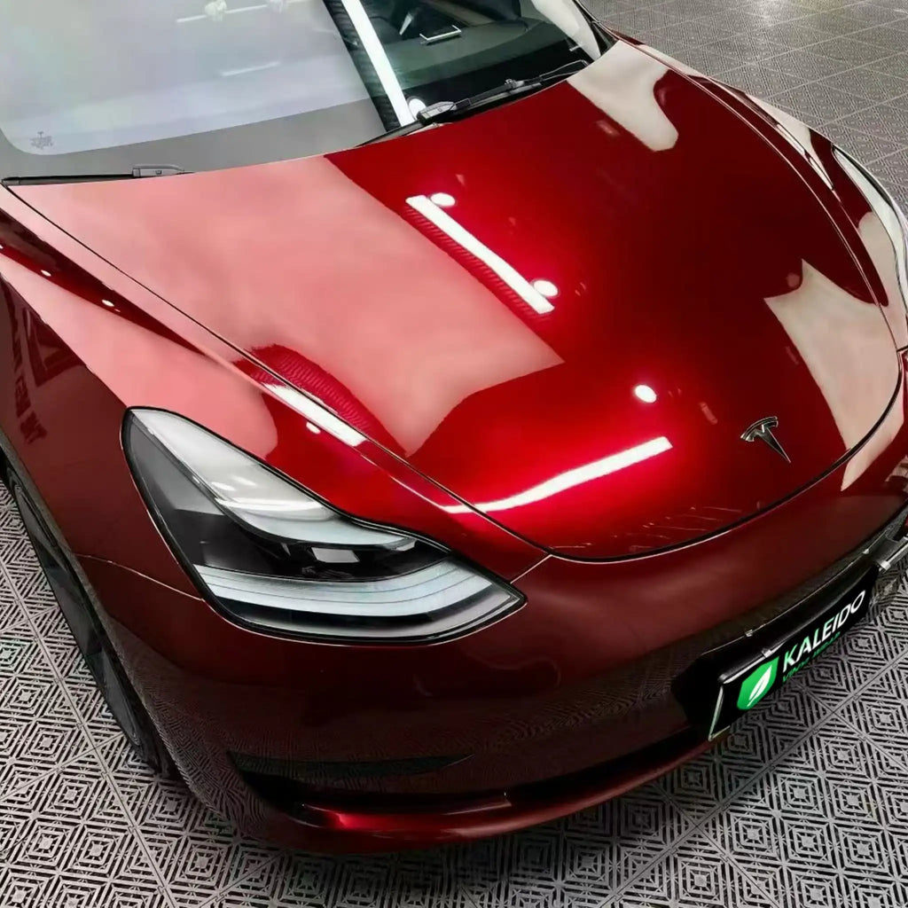 Close-up of Gloss Metallic Dragon Blood vinyl on Tesla Model 3 front-right hood area - Kaleido