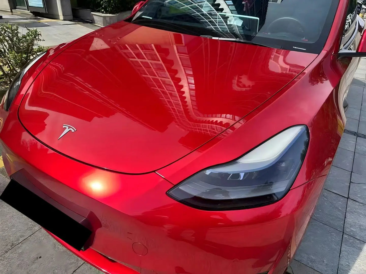 Gem Red vinyl wrap on Tesla Model Y front-left hood area - deep red metallic finish - Kaleido