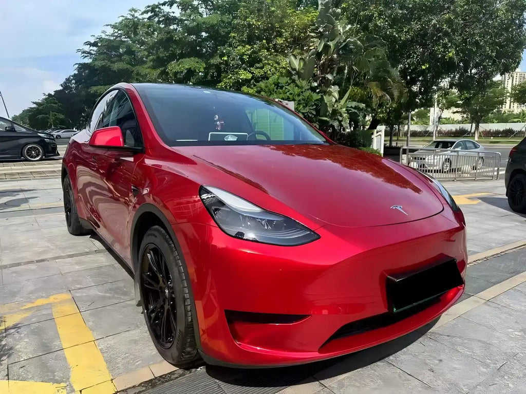 Gem Red metallic wrap on Tesla Model Y front-right corner - showcasing bumper and headlight details - Kaleido