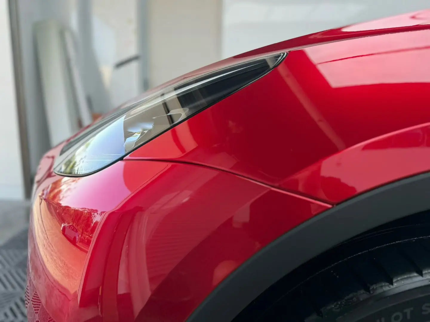 Detailed shot of Gem Red wrap on Tesla Model Y left headlight area - precise installation showcase - Kaleido