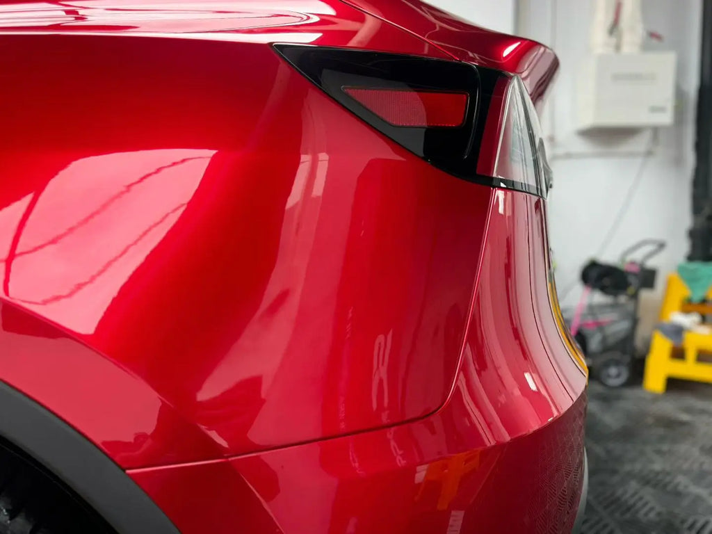 Gem Red metallic film on Tesla Model Y left rear bumper - detailed close-up - Kaleido