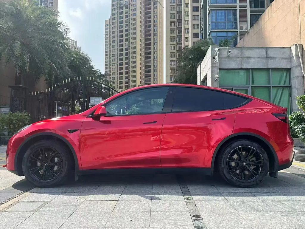 Tesla Model Y in Gem Red gloss metallic vinyl - side profile in natural light showing deep ruby red color - Kaleido
