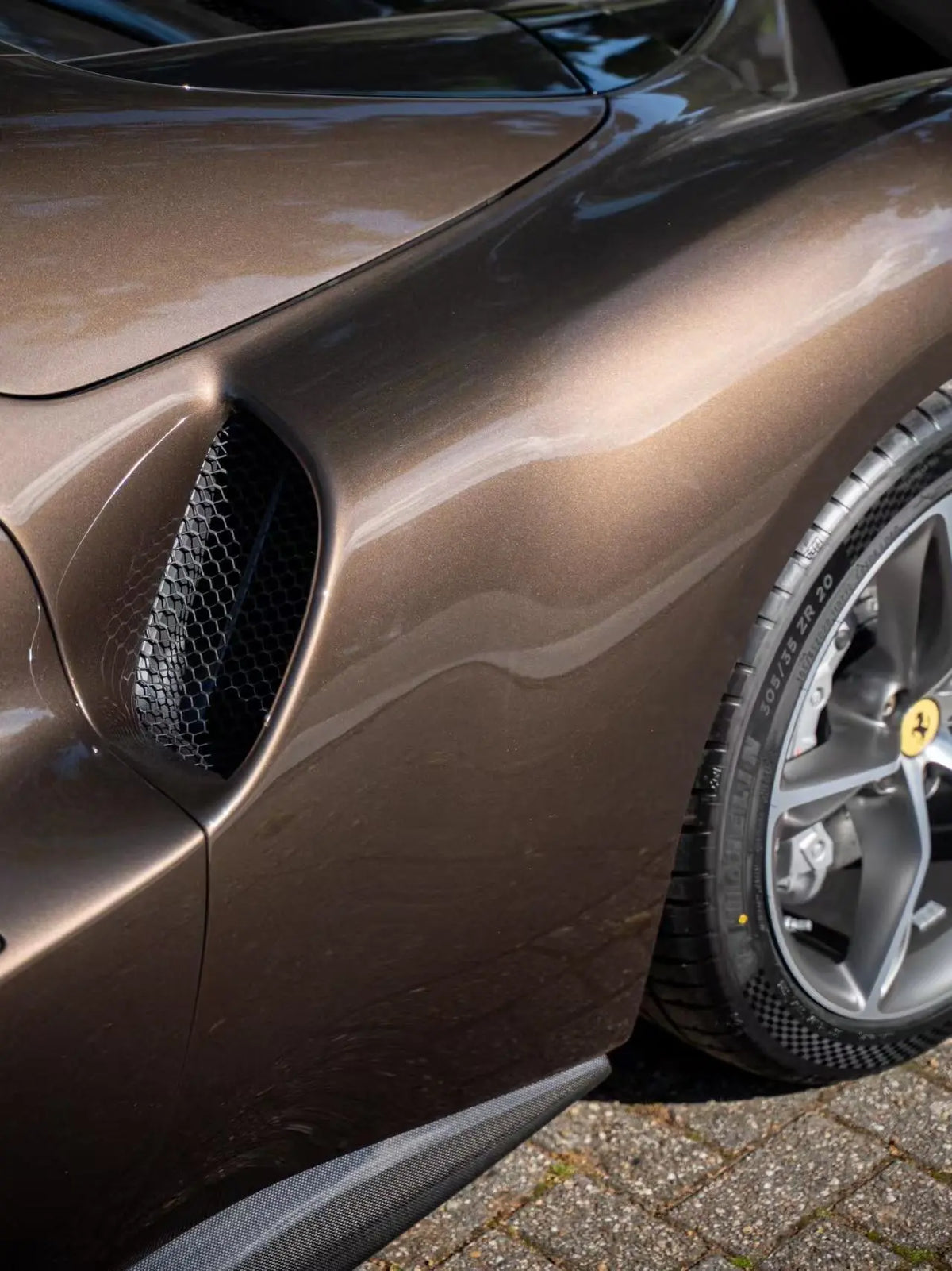Mocha Truffle metallic wrap on Ferrari 296 GTS fender - showcasing sculpted body lines - Kaleido
