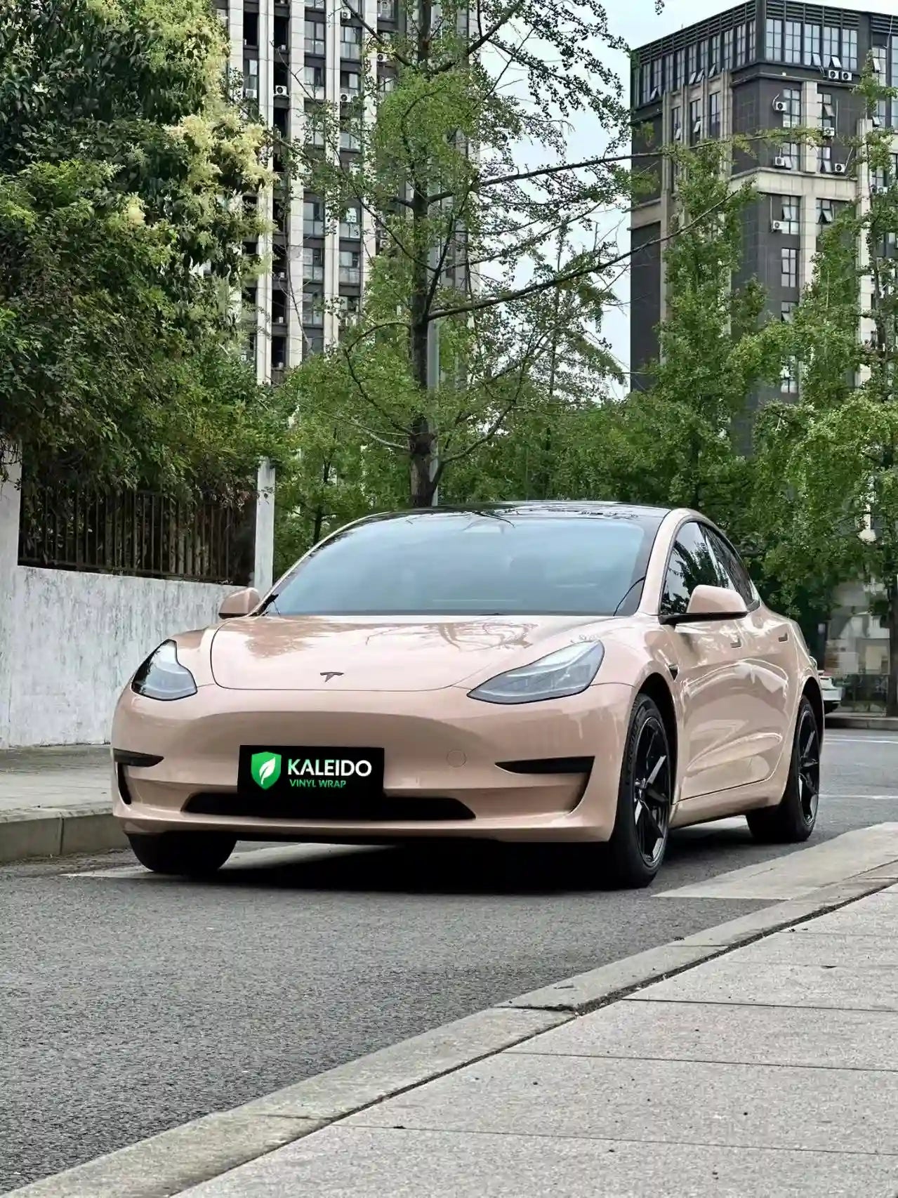 Tesla Model 3 in Gloss Milktea vinyl wrap - front-left angle with warm beige gloss - Kaleido