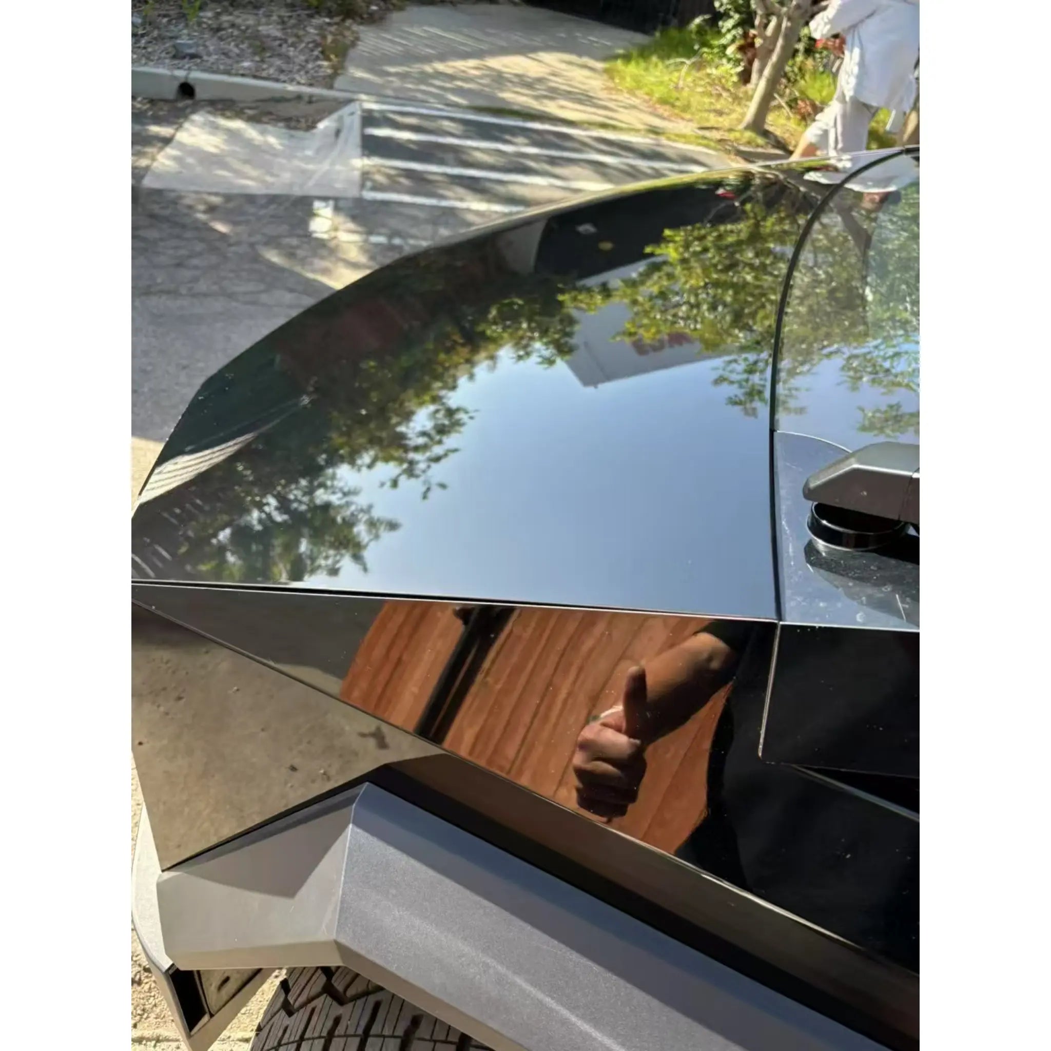 Close-up detail of the Gloss Piano Black vinyl on the hood of a Cybertruck - Mirror finish on stainless steel - Kaleido