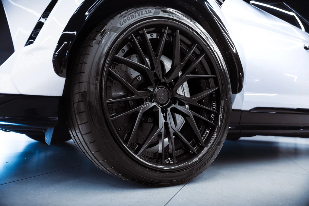 Close-up detail of Gloss Piano White vinyl near the rear wheel of a Lamborghini Urus - Kaleido