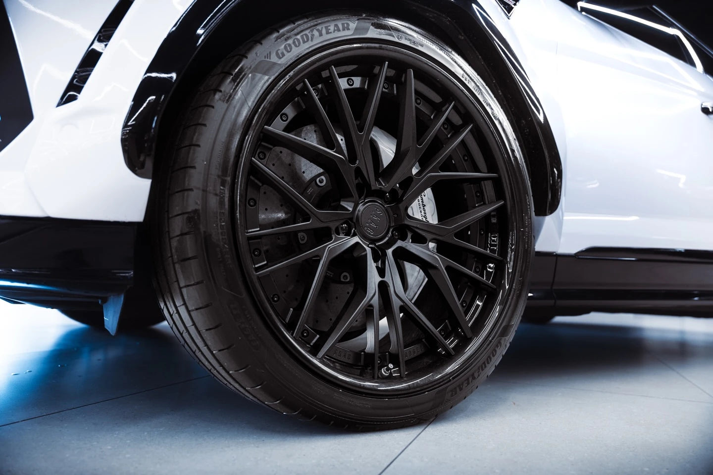 Close-up detail of Gloss Piano White vinyl near the rear wheel of a Lamborghini Urus - Kaleido