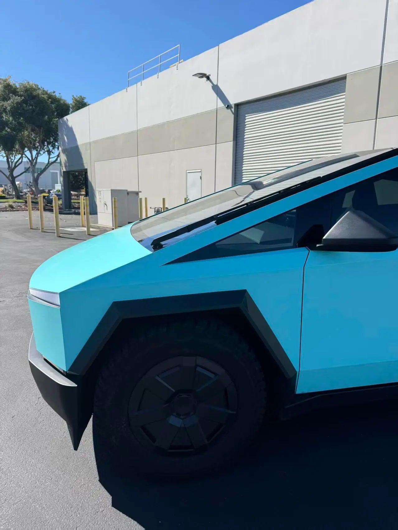 Gloss Tiffany vinyl wrap on Tesla Cybertruck front-left corner - iconic blue-green color on angular body - Kaleido