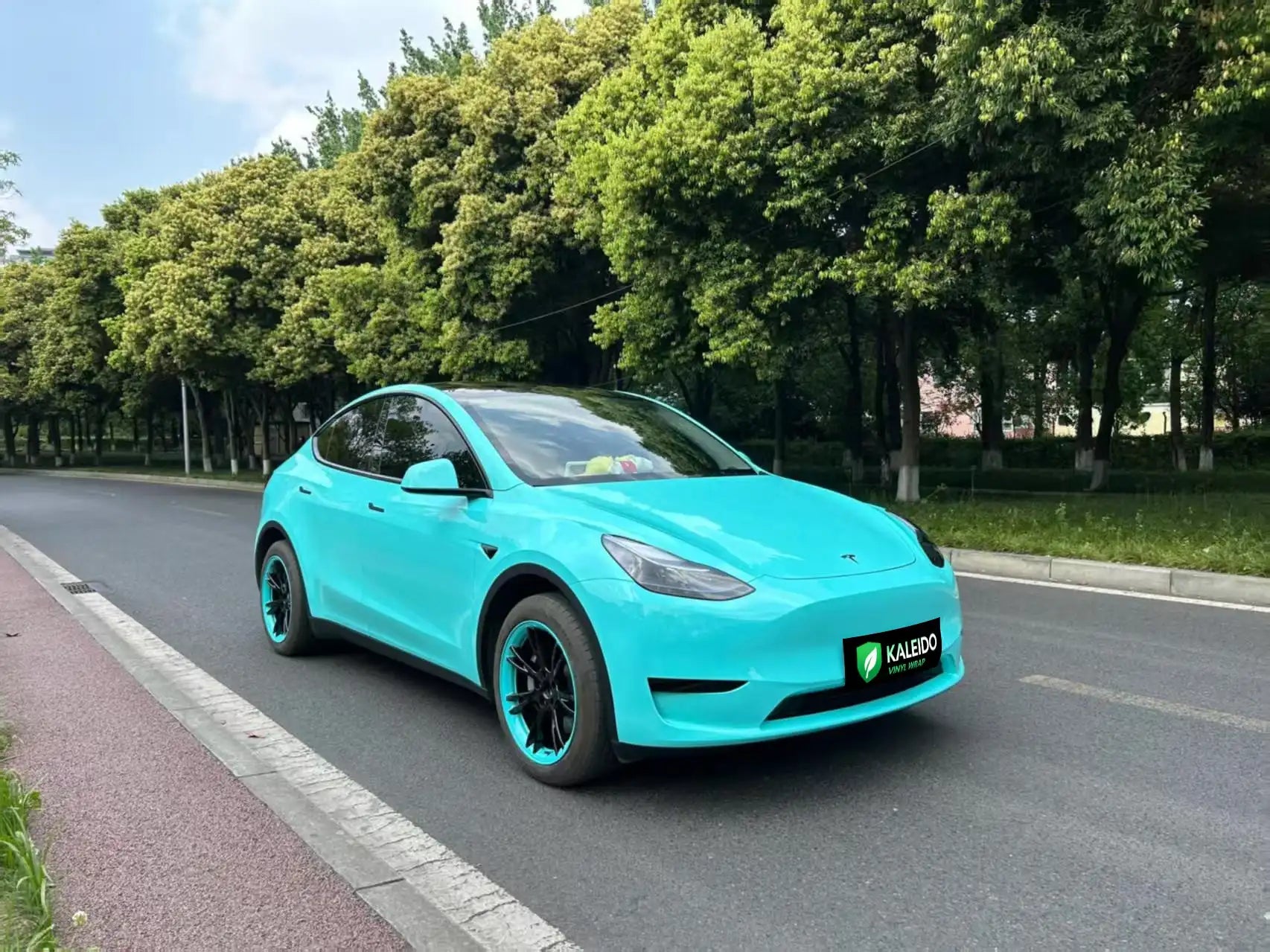Wide front-right view of Tesla Model Y in Gloss Tiffany blue-green vinyl - Kaleido