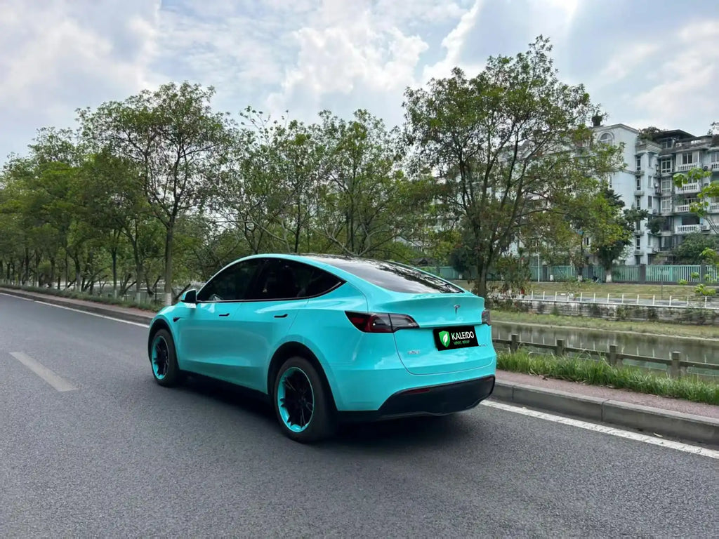 Wide rear-left view of Tesla Model Y in Gloss Tiffany blue-green vinyl - Kaleido