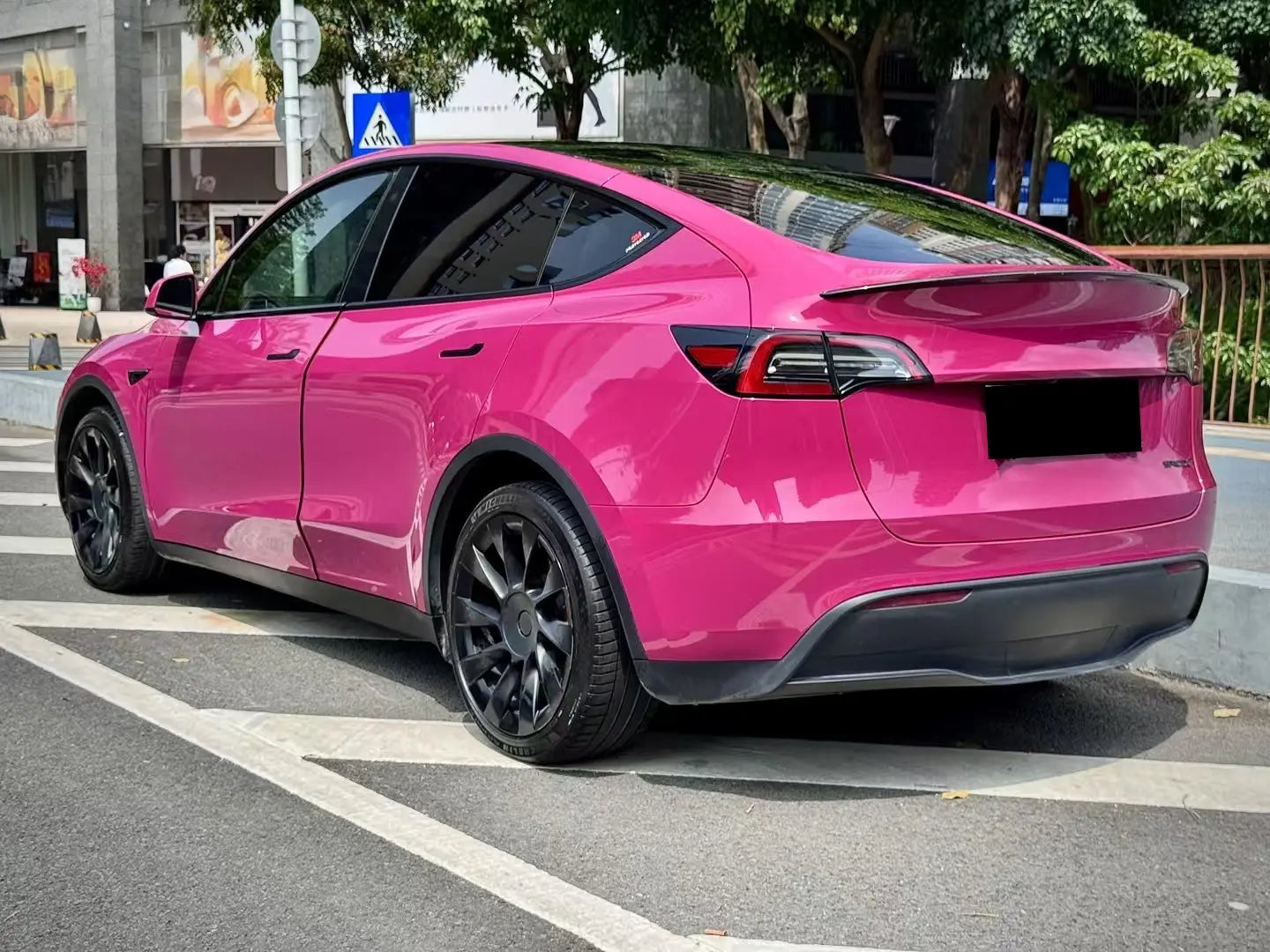 Wide rear-left view of Tesla Model Y in Ruby Night Star gloss vinyl - full SUV profile - Kaleido