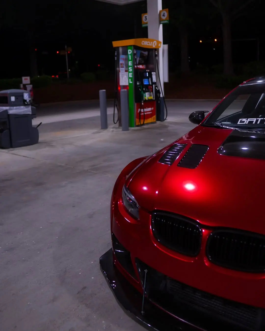 Front-right detail shot of Glossy Metallic Vampire Red vinyl on a widebody BMW E92 bumper - Kaleido