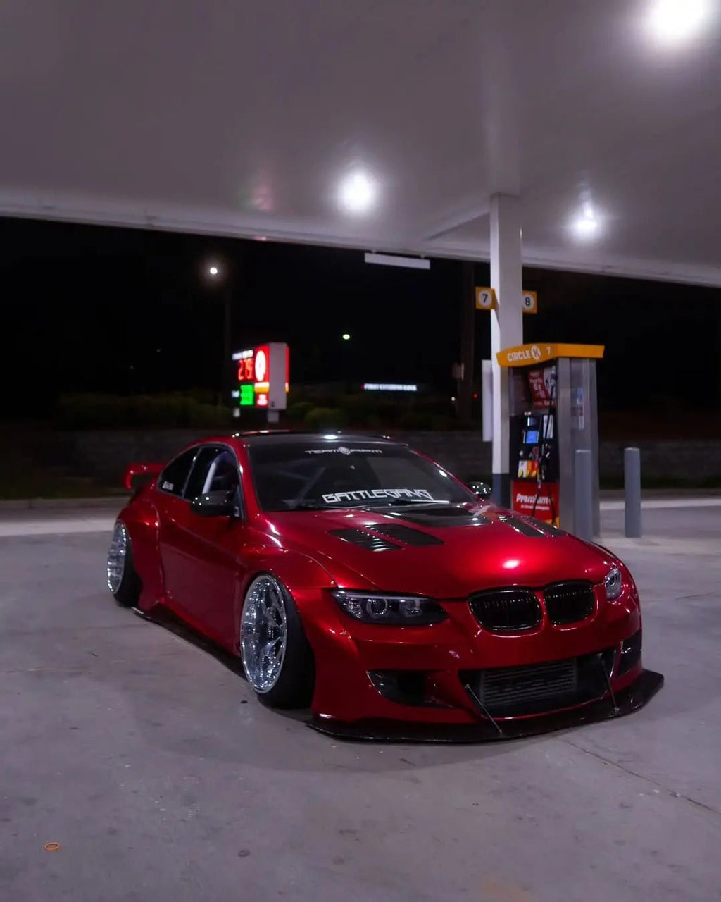 Wide front-right view of a Glossy Metallic Vampire Red wrapped widebody BMW E92 - Kaleido