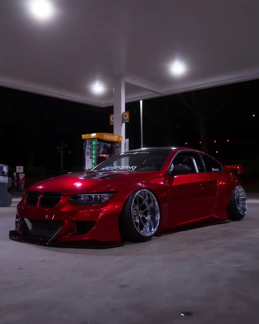 Wide front-left view of a widebody BMW 3 Series (E92) coupe in Glossy Metallic Vampire Red wrap - Kaleido