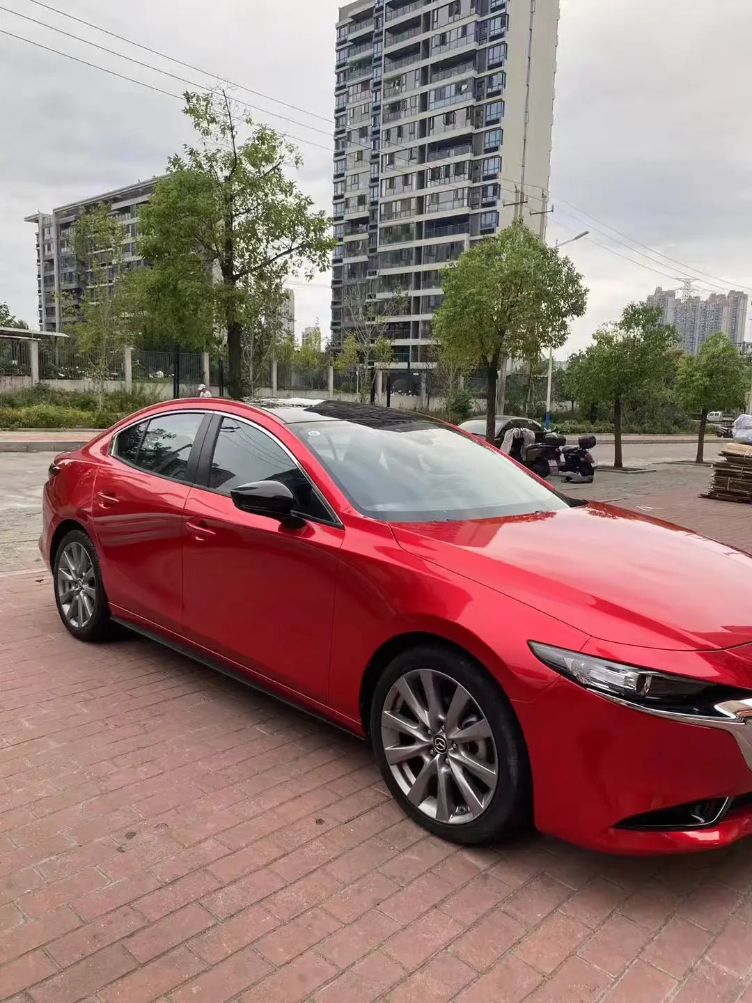 Glossy Metallic Vampire Red wrap on the front-right of a Mazda 3 sedan - Kaleido